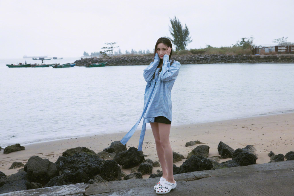 杨幂蓝色衬衣短裤现身海边沙滩，飘逸长发优雅迷人
